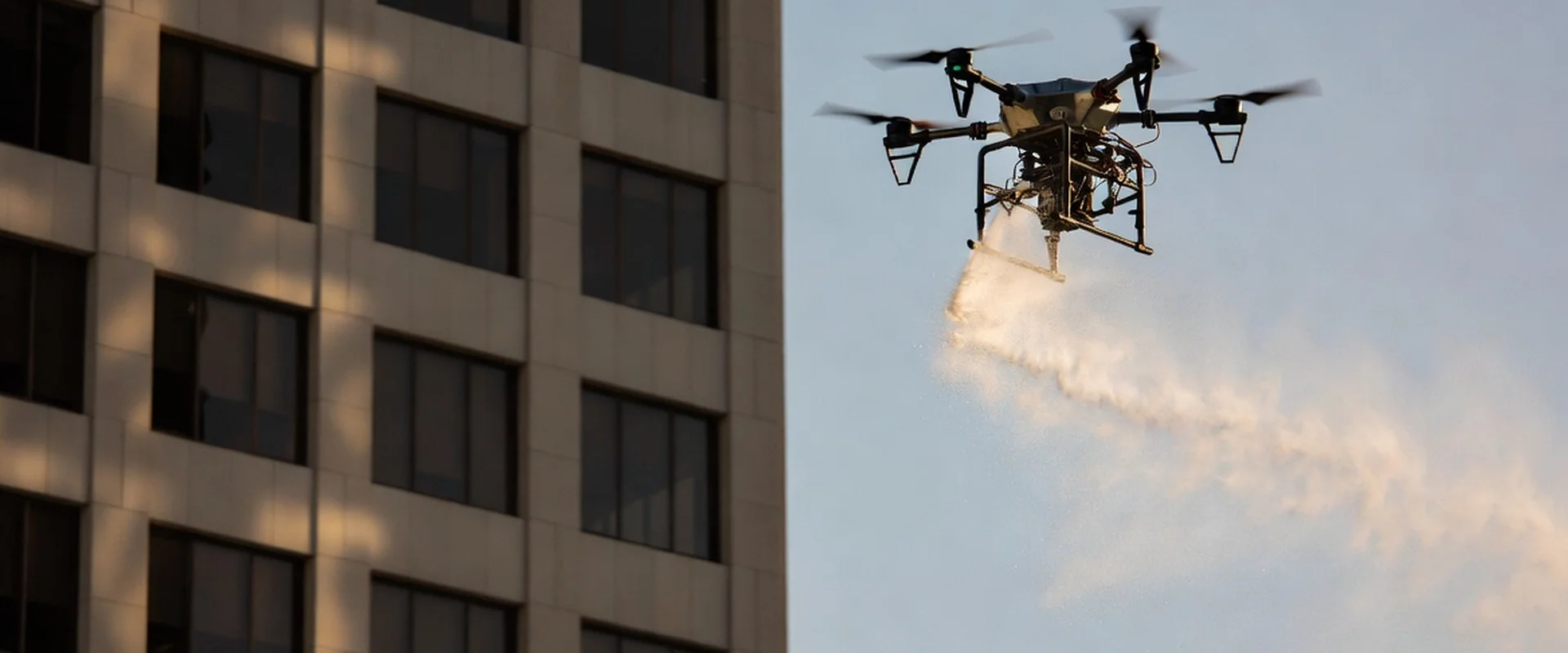 Industrial cleaning drone spraying water on commercial building facade