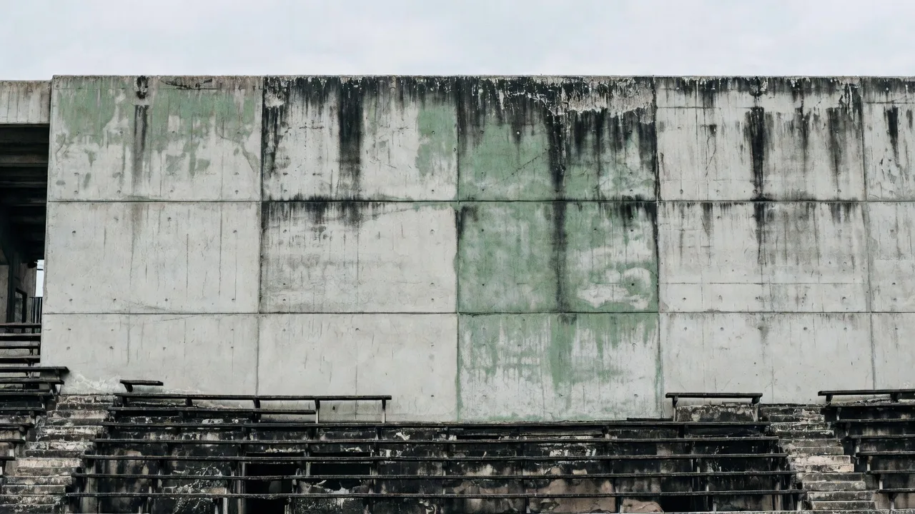 Dirty stadium wall covered in algae and mold stains before AeroWash drone cleaning service